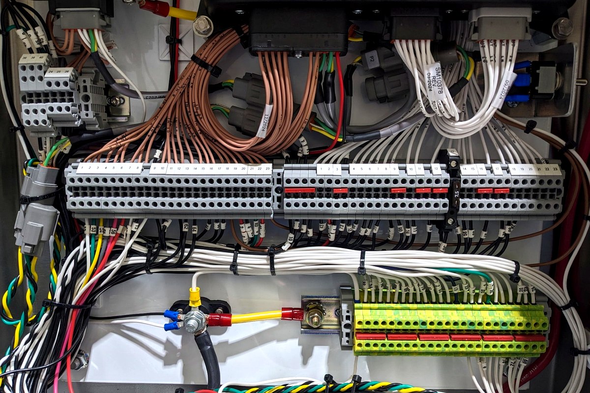QCS box build interior — DIN rail terminal blocks, panel wiring, and circuit protection fully assembled